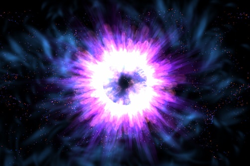A vibrant and colorful burst of energy emanates from a central point, surrounded by swirling blue and purple hues. The intense brightness at the center contrasts with the darker outer regions, creating a sense of depth and motion.