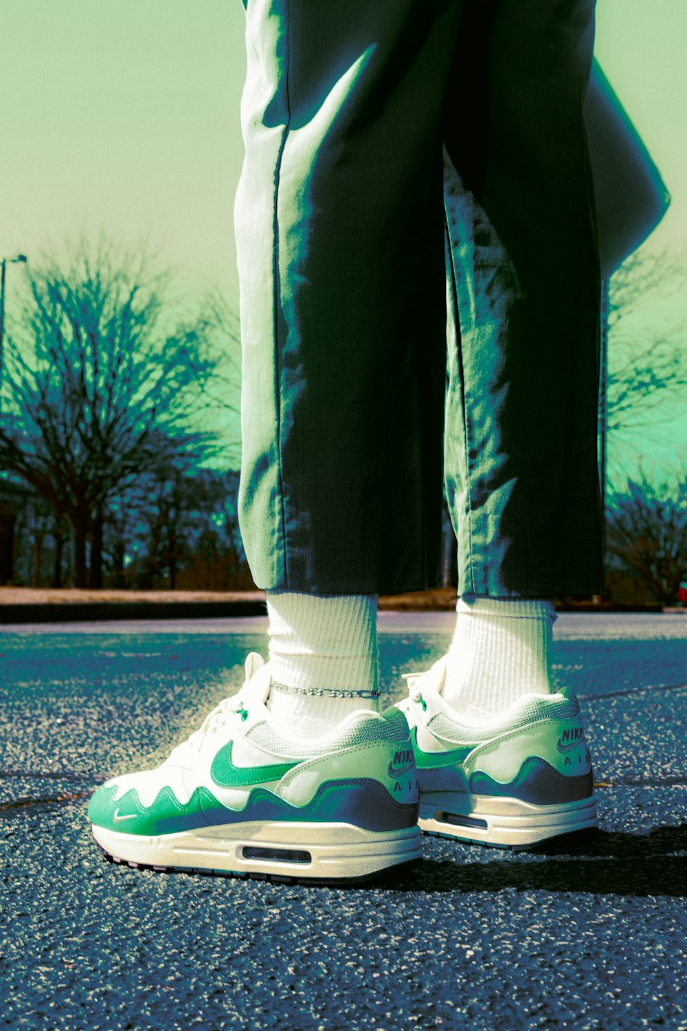 a person wearing green and white shoes standing on a street