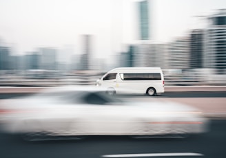 a white van driving down a street next to tall buildings