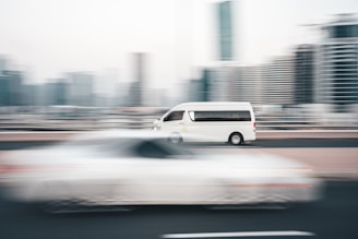 a white van driving down a street next to tall buildings