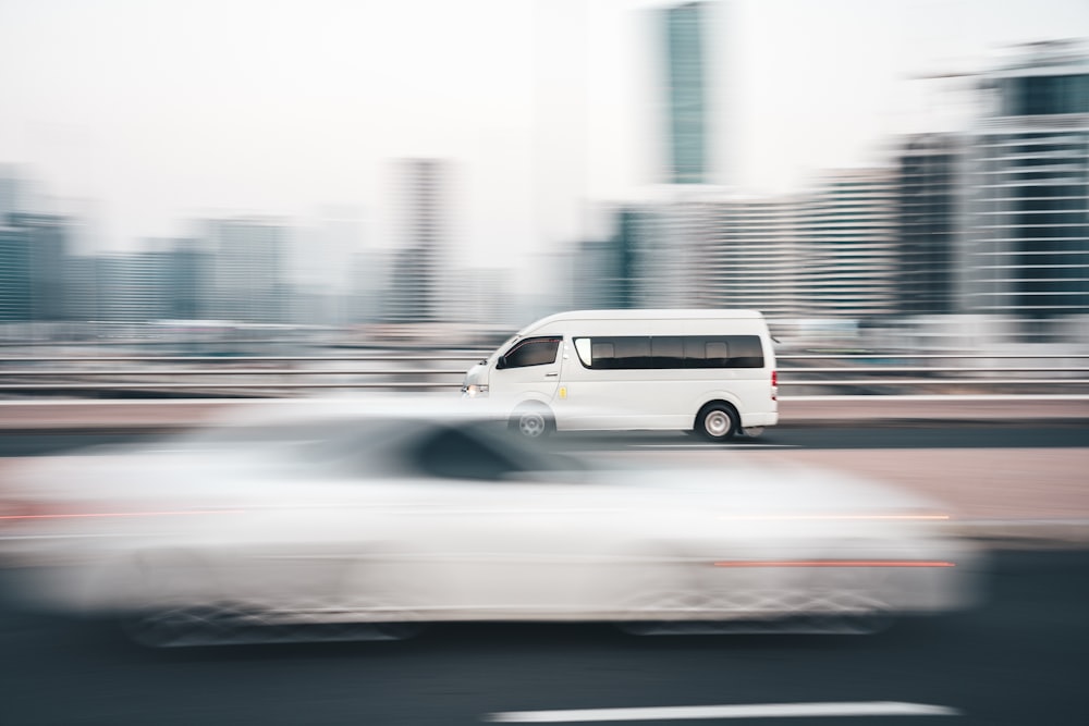 a white van driving down a street next to tall buildings