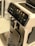 A sleek coffee machine with a user-friendly interface featuring options for various coffee types. The front panel is glossy with a digital display and several touch icons. The machine's metallic drip tray is visible at the bottom.