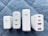Four white charging adapters are arranged vertically on a quilted gray-blue surface. Each adapter differs slightly in design and size but commonly features USB ports, with some labeled for power delivery (PD) and specific wattages.