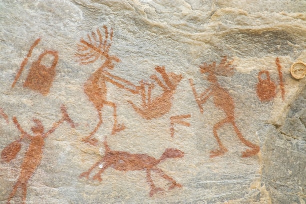 a rock painting of people and animals on it