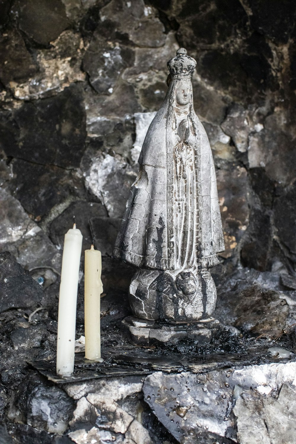 a candle and a statue on a stone surface