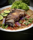 A colorful plate with assorted volcanes including arrachera and chorizo argentino, garnished with lime wedges.