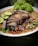 A vibrant plate of sizzling pork sisig garnished with green onions and lime.