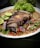 A vibrant plate of sizzling pork sisig garnished with green onions and lime.