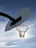 Close-up of a handmade basketball net hanging on an outdoor hoop with sunlight streaming through.