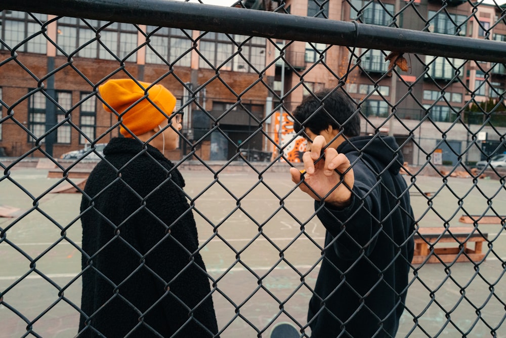 a couple of men standing next to each other behind a fence