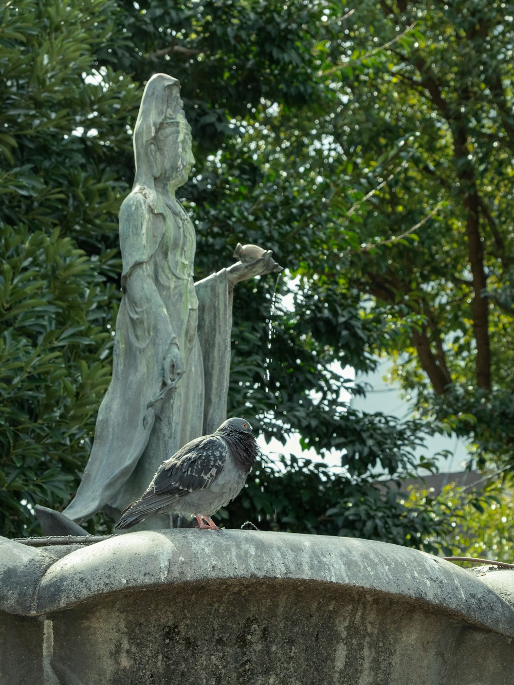 a bird is perched on the edge of a statue