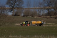a tractor pulling a trailer behind it through a field