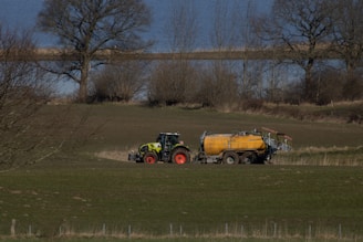 a tractor pulling a trailer behind it through a field