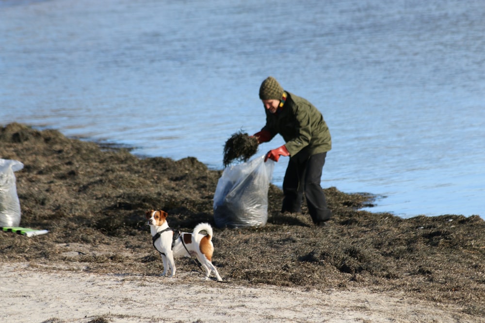 Ein Mann und ein Hund am Strand mit einem Sack Müll