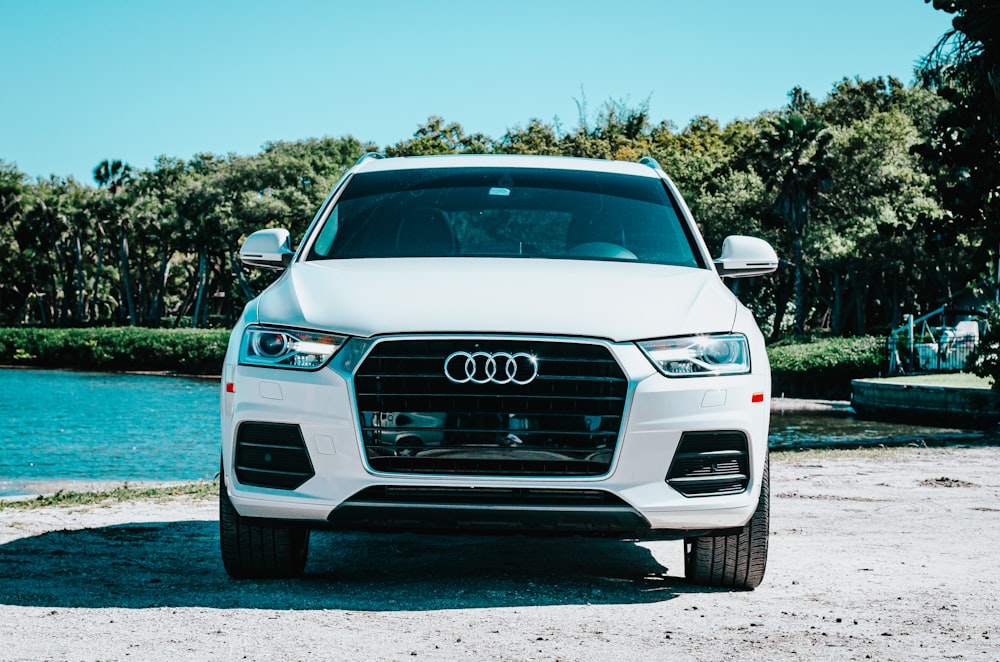 a white car parked in front of a body of water