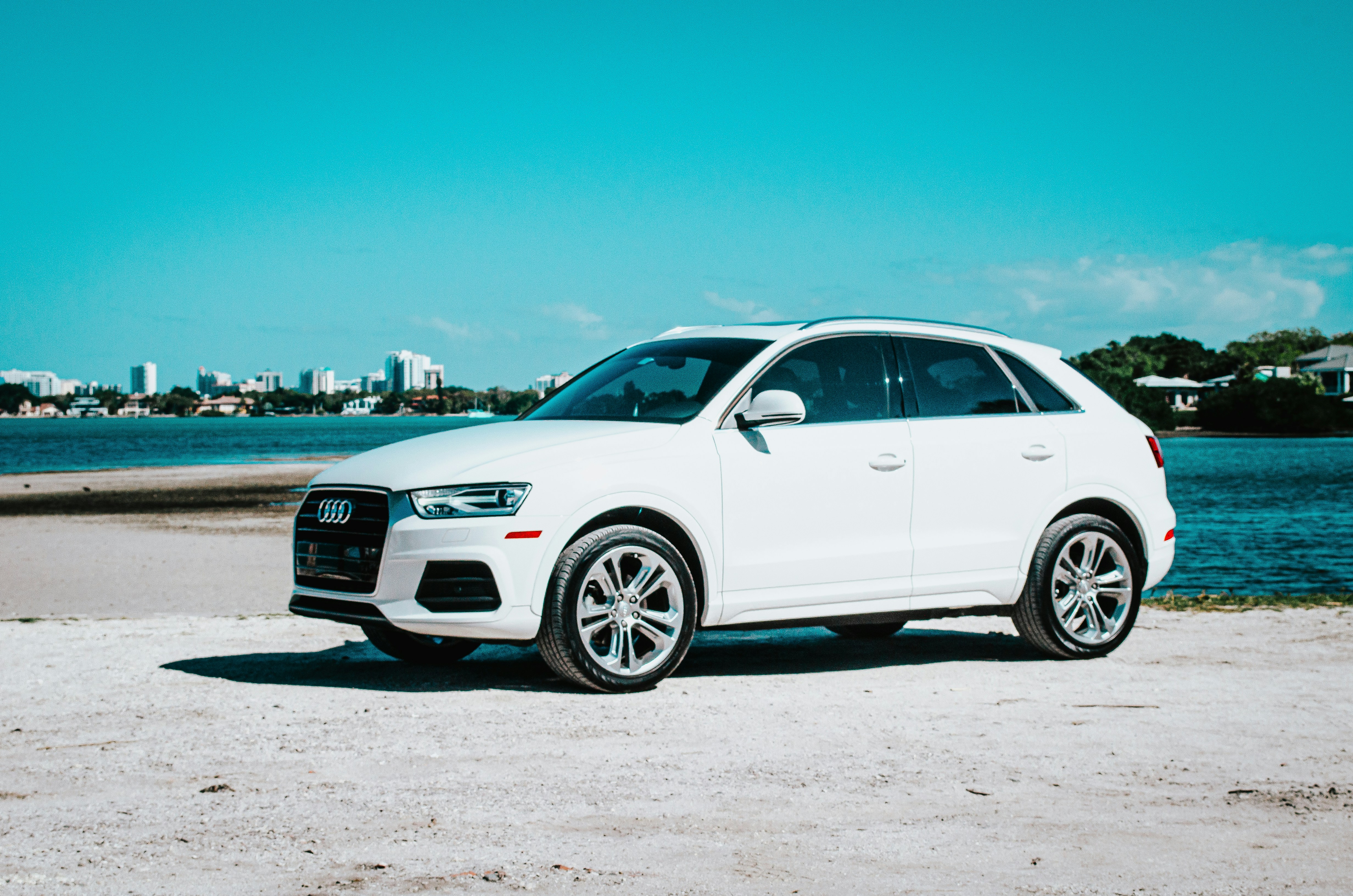 a white car parked on a beach next to a body of water
