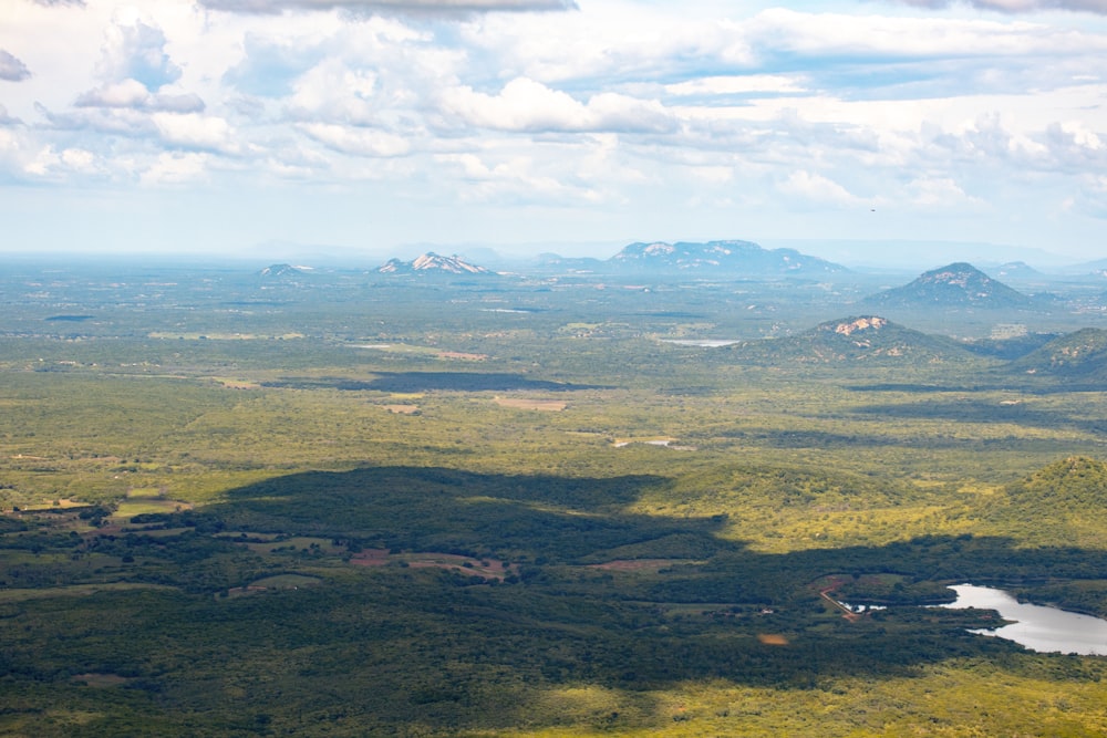 an aerial view of a valley with a lake and mountains in the background