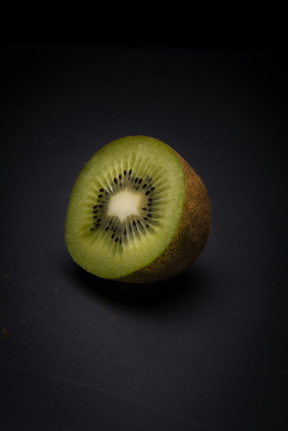 a kiwi cut in half on a black surface