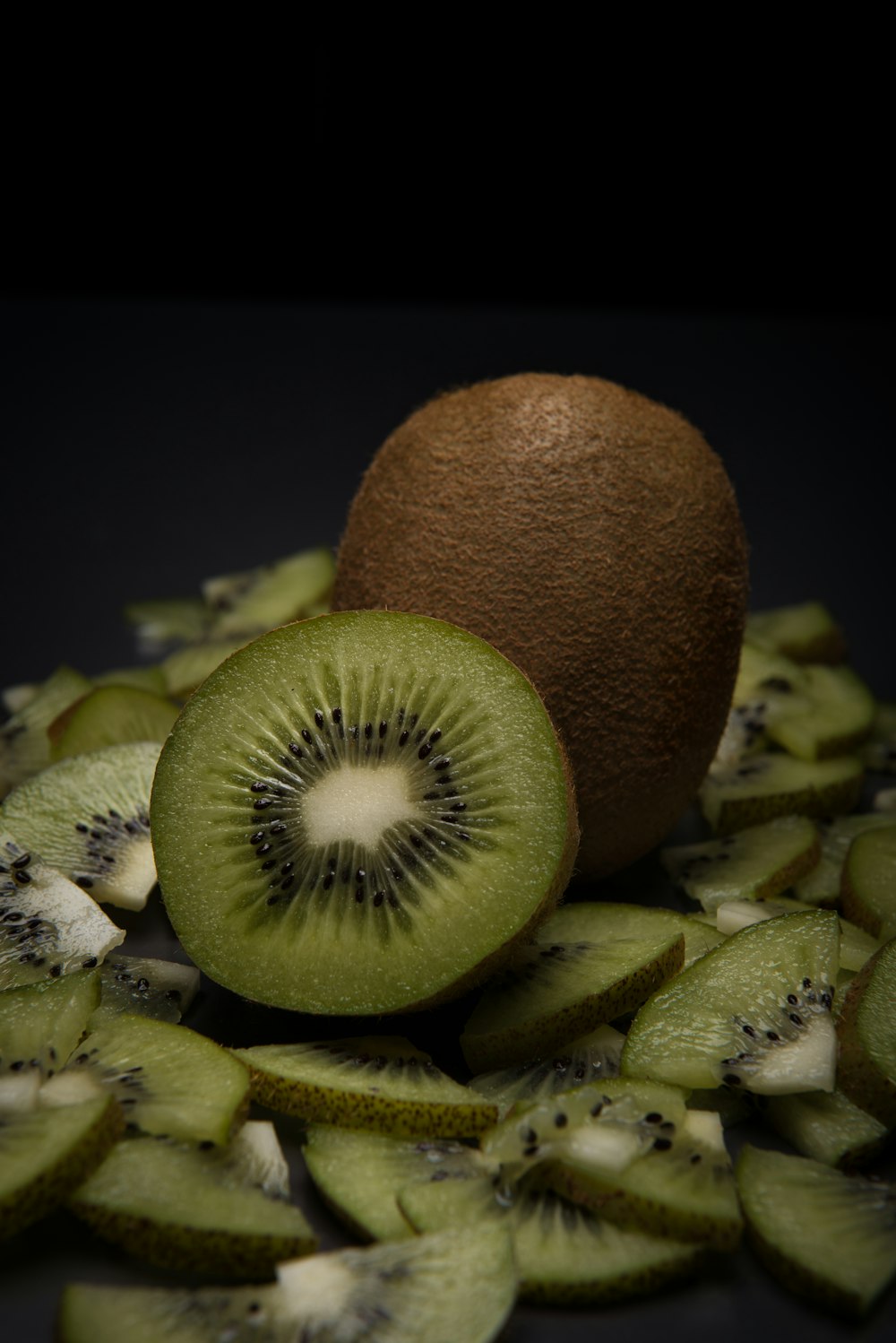 a kiwi sliced in half on a pile of kiwi slices