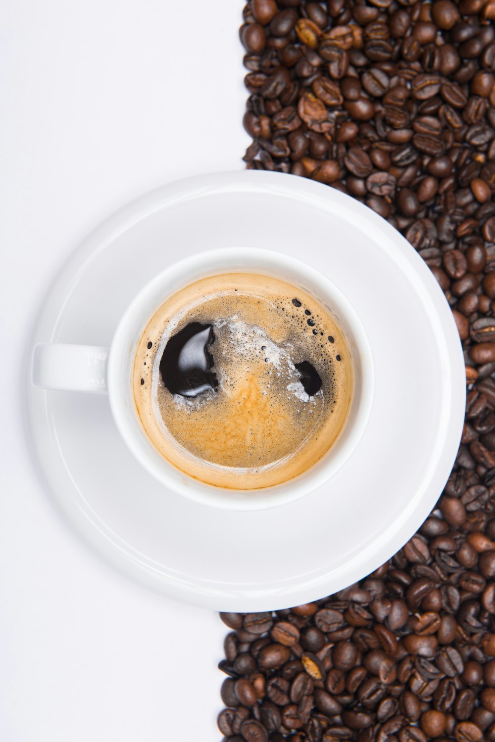 a cup of coffee sitting on top of a pile of coffee beans