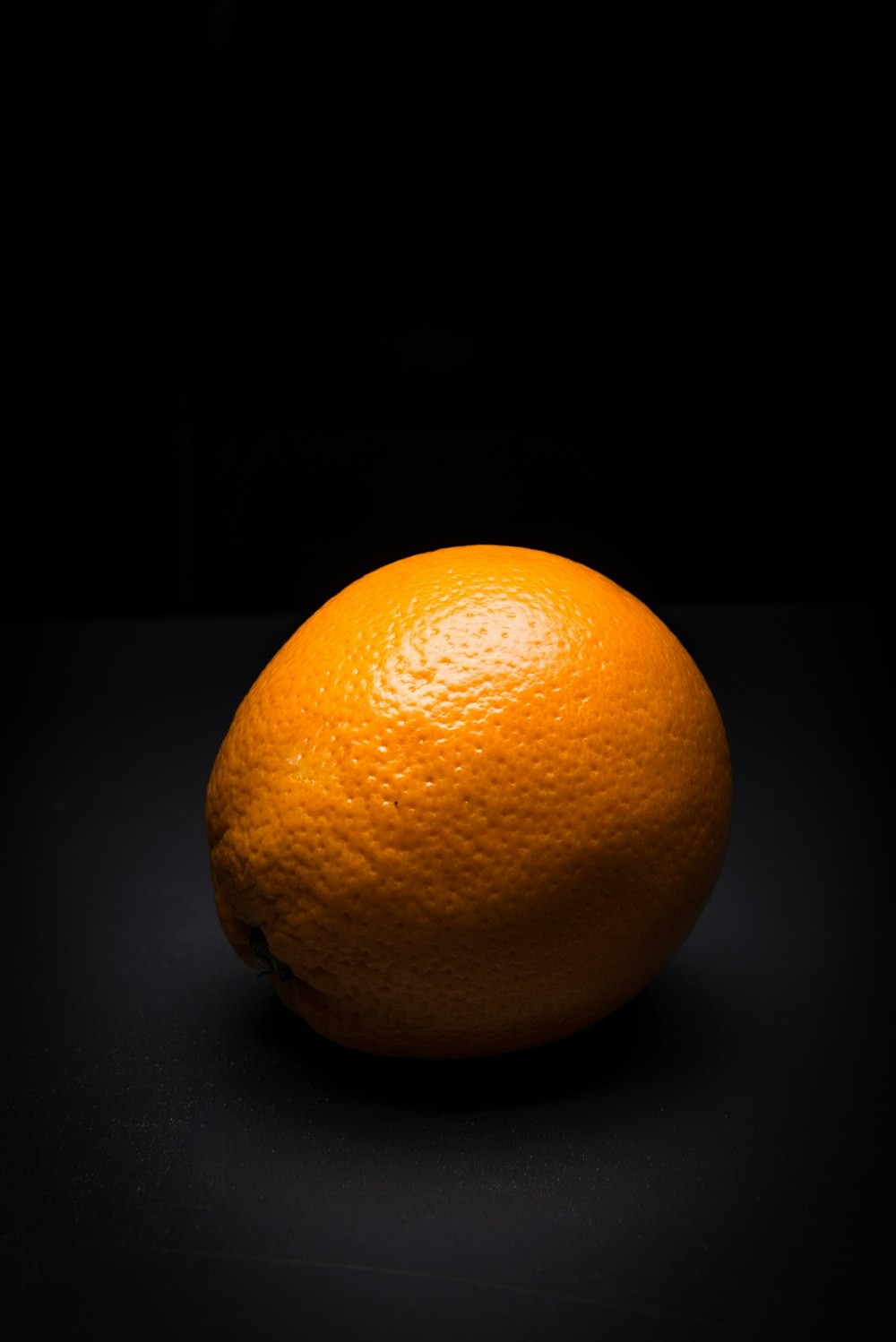 an orange sitting on top of a black table
