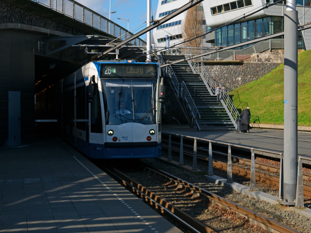 a blue and white train pulling into a train station