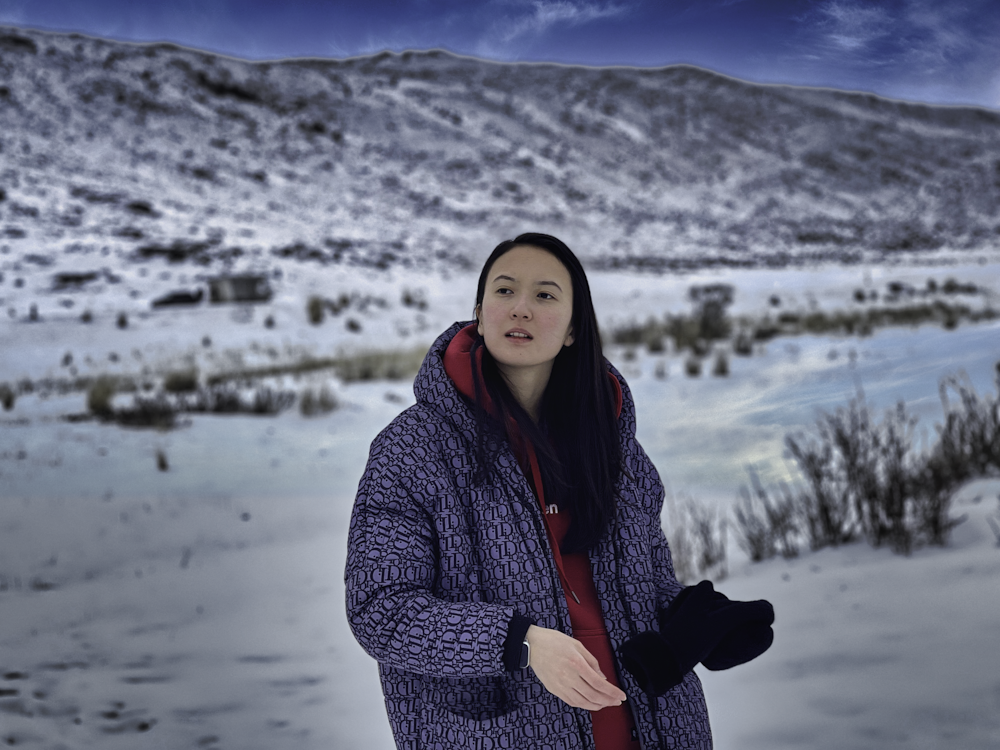 a woman standing in the snow with a mountain in the background