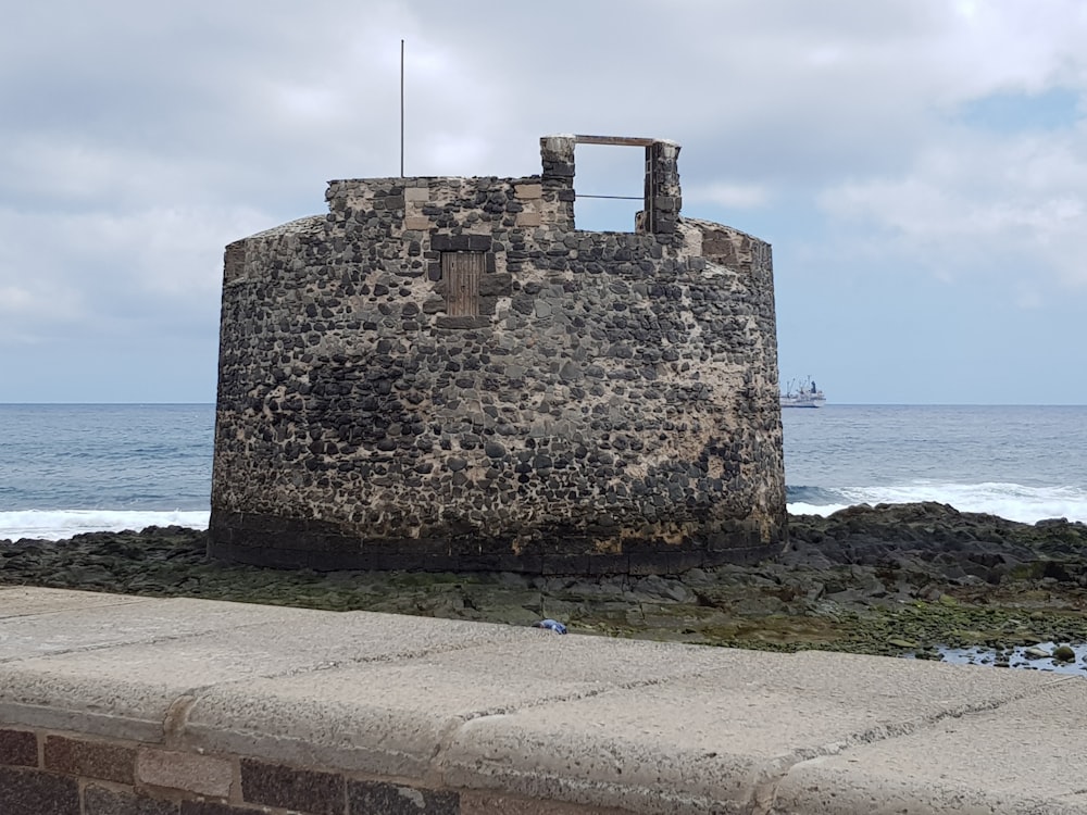 a stone tower sitting on top of a beach next to the ocean