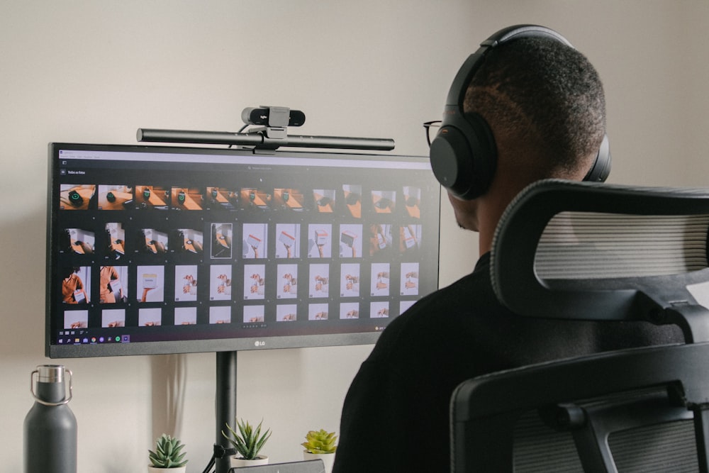 a man sitting in front of a computer monitor wearing headphones