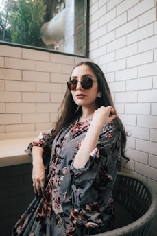 a woman wearing sunglasses standing in front of a window