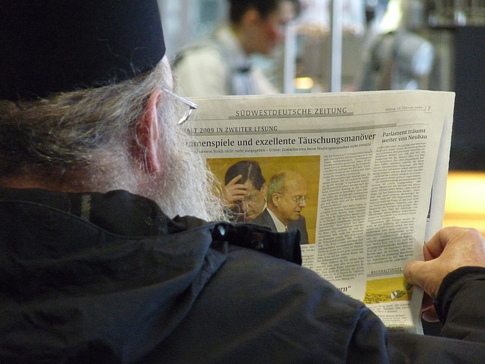 a man reading a newspaper while sitting down