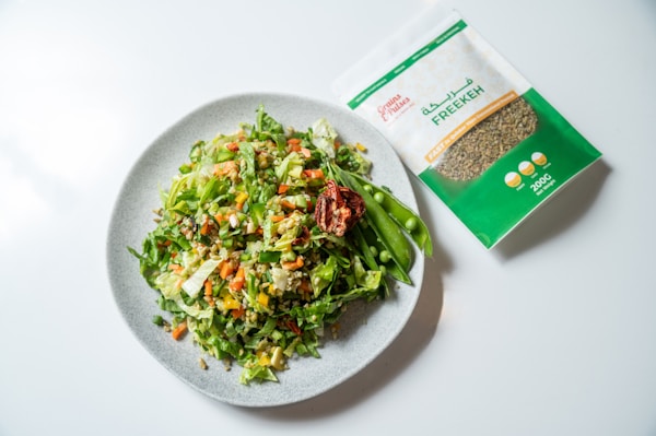 A white plate topped with a salad next to a bag of seeds