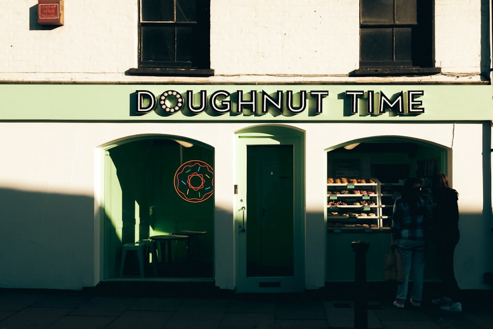 a couple of people standing outside of a doughnut shop