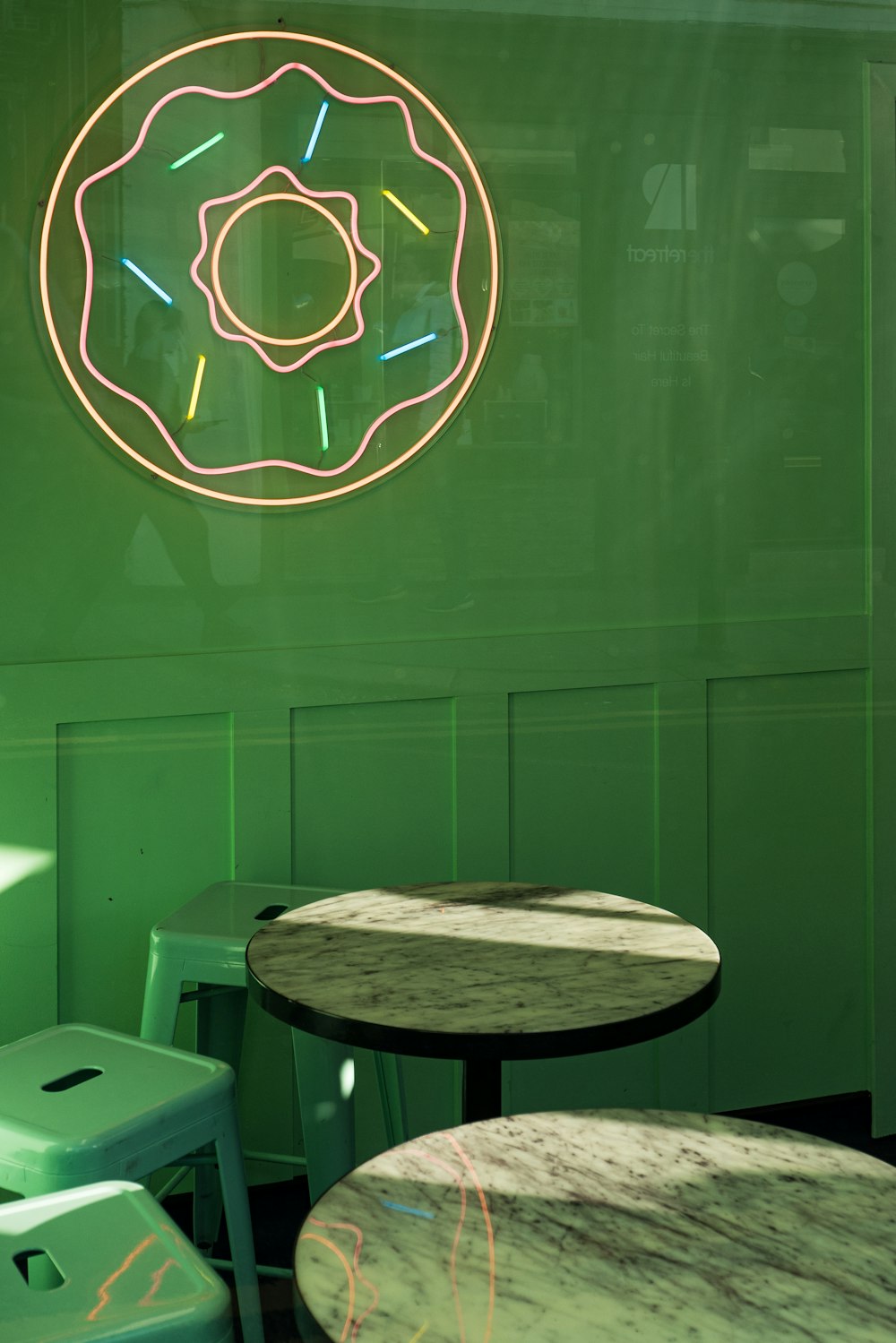 a green wall with a neon donut on it