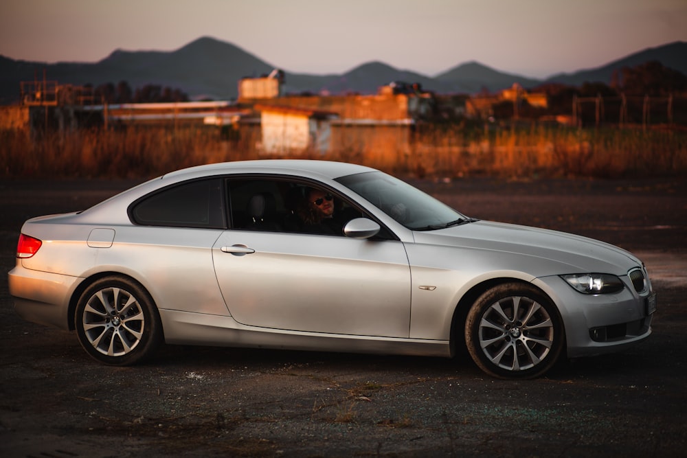 a silver car parked in a parking lot with mountains in the background