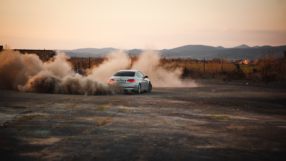 a white car driving down a dirt road