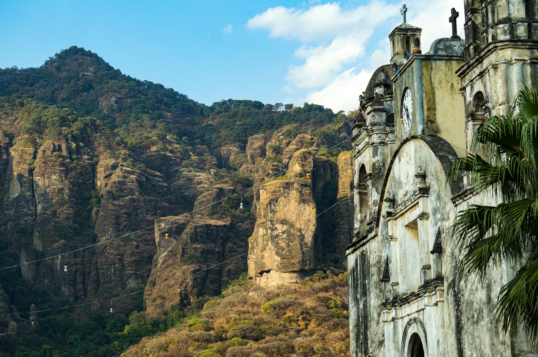 The bell tower of a colonial church in Tepoztlán against the green cliffs of the Sierra del Tepozteco, one reason Tepoztlan is worth visiting