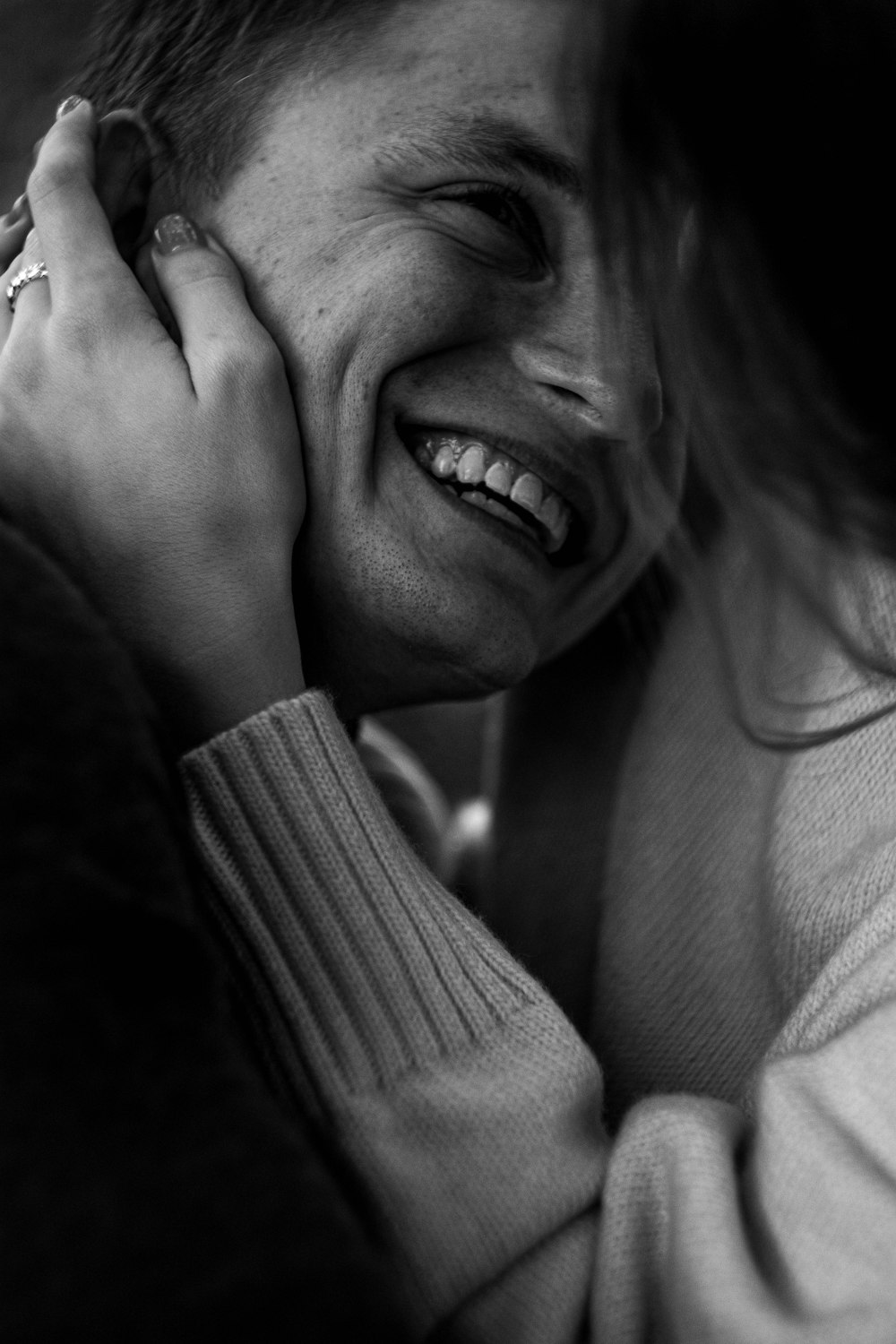 a woman smiling and holding her hand to her face