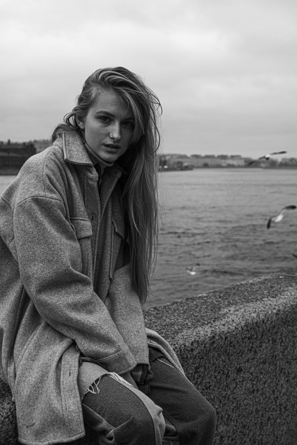 a woman sitting on a wall next to a body of water