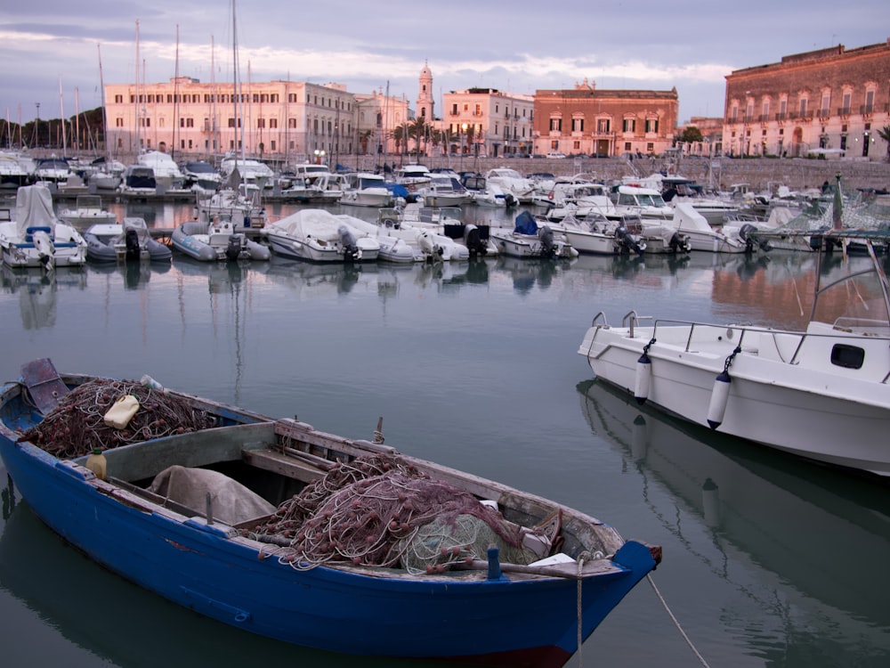 a blue boat sitting in the middle of a harbor filled with lots of boats