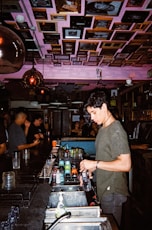 a man standing at a bar making a drink