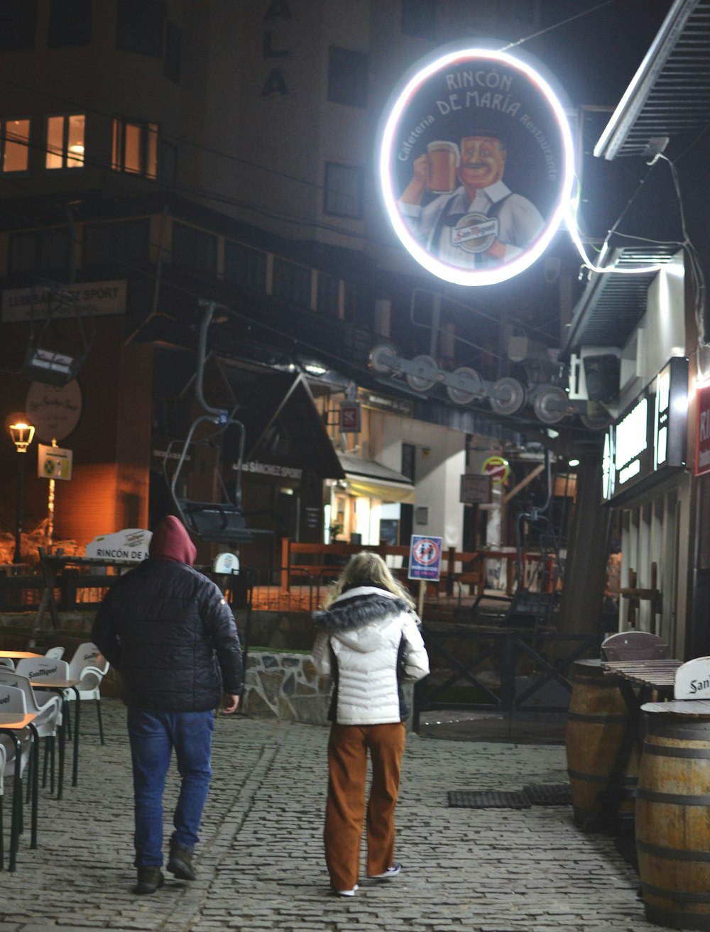 two people walking down a cobblestone street at night