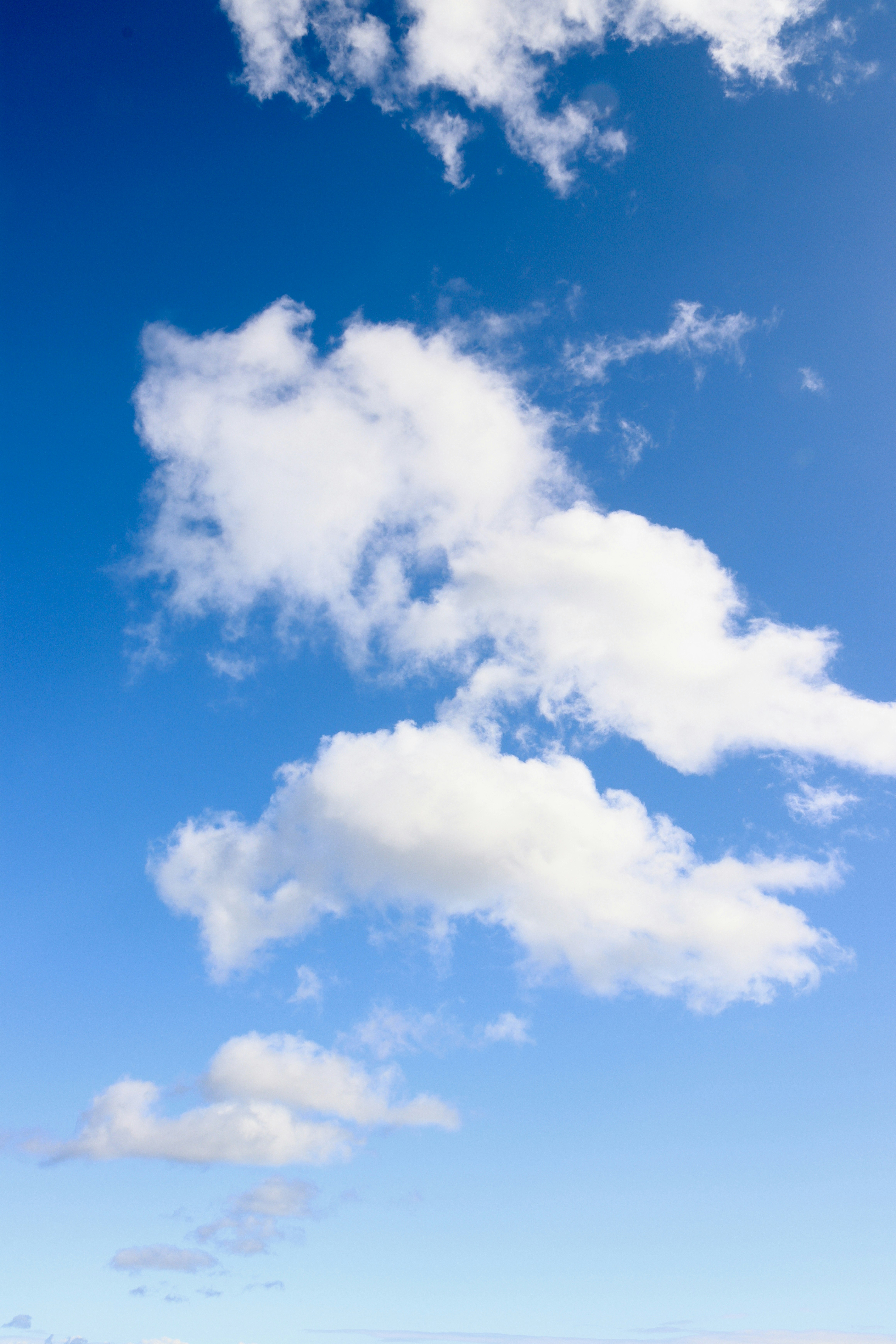 a person standing on a beach with a surfboard under a cloudy blue sky
