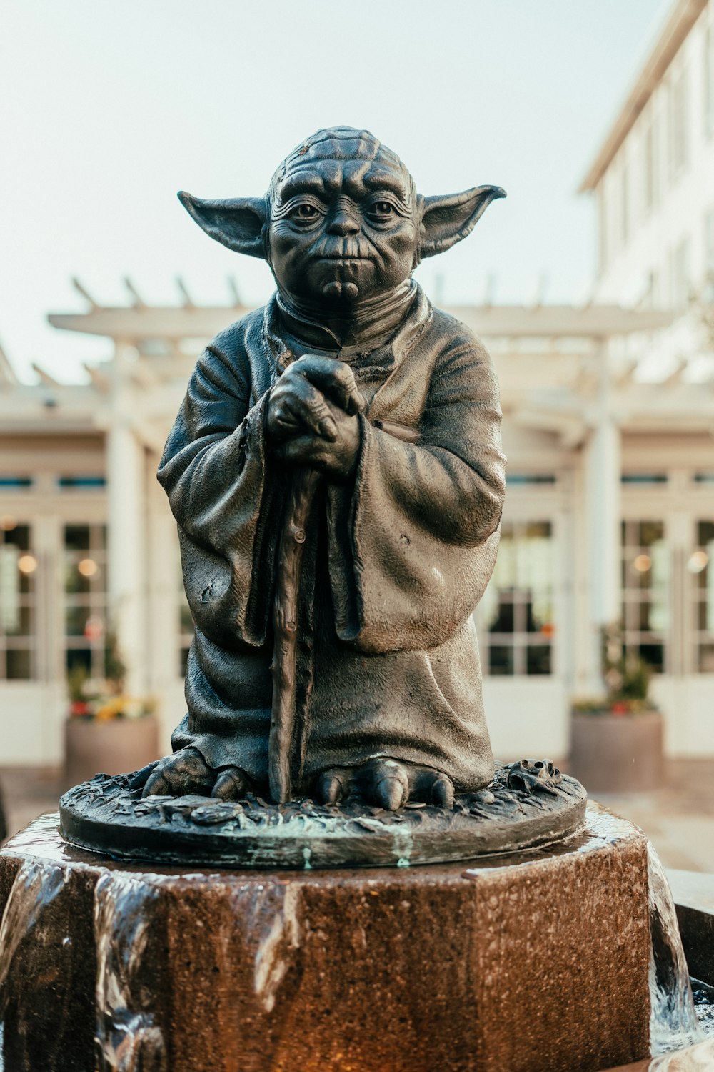 a statue of yoda holding a staff in front of a building
