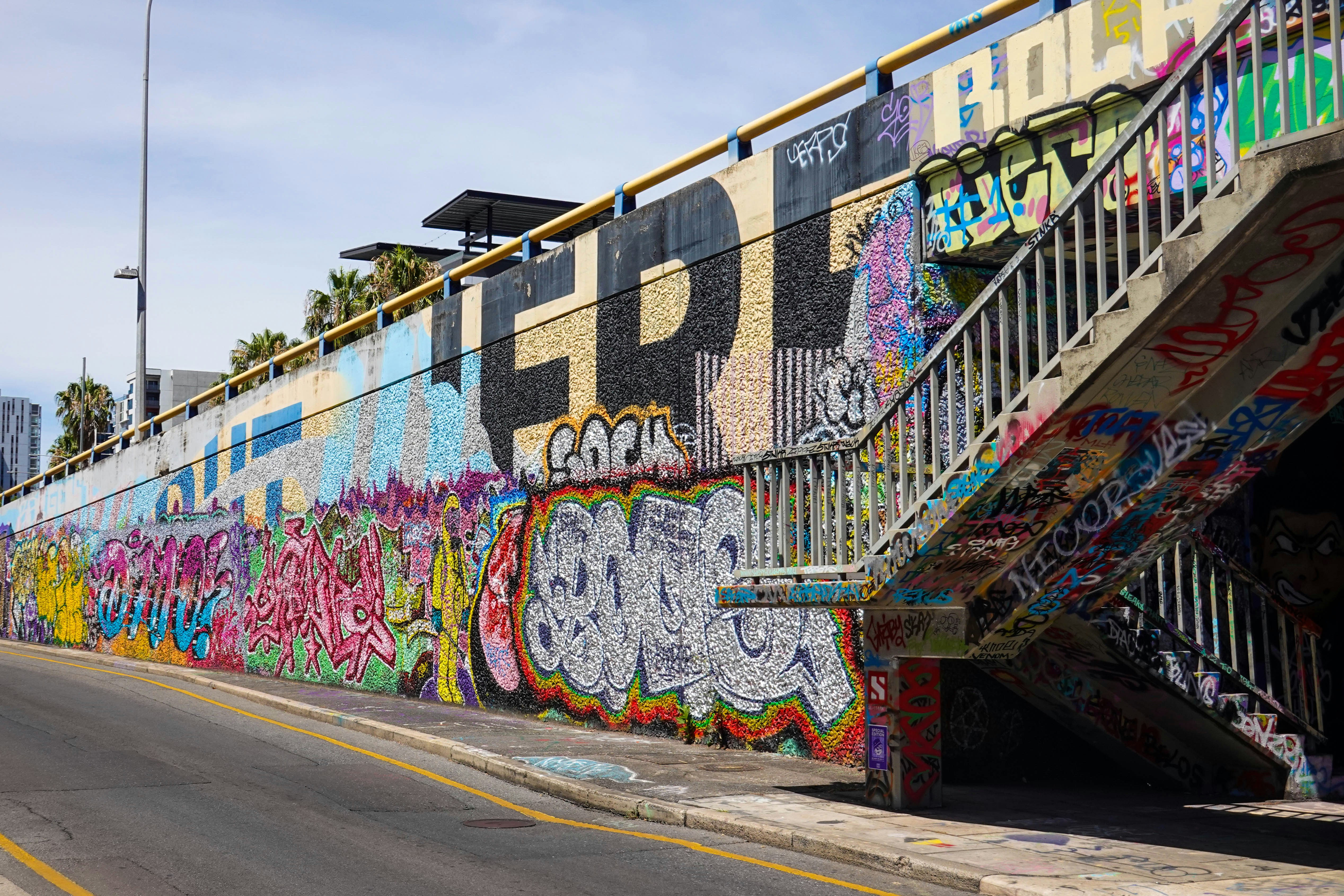 a wall covered in graffiti next to a street