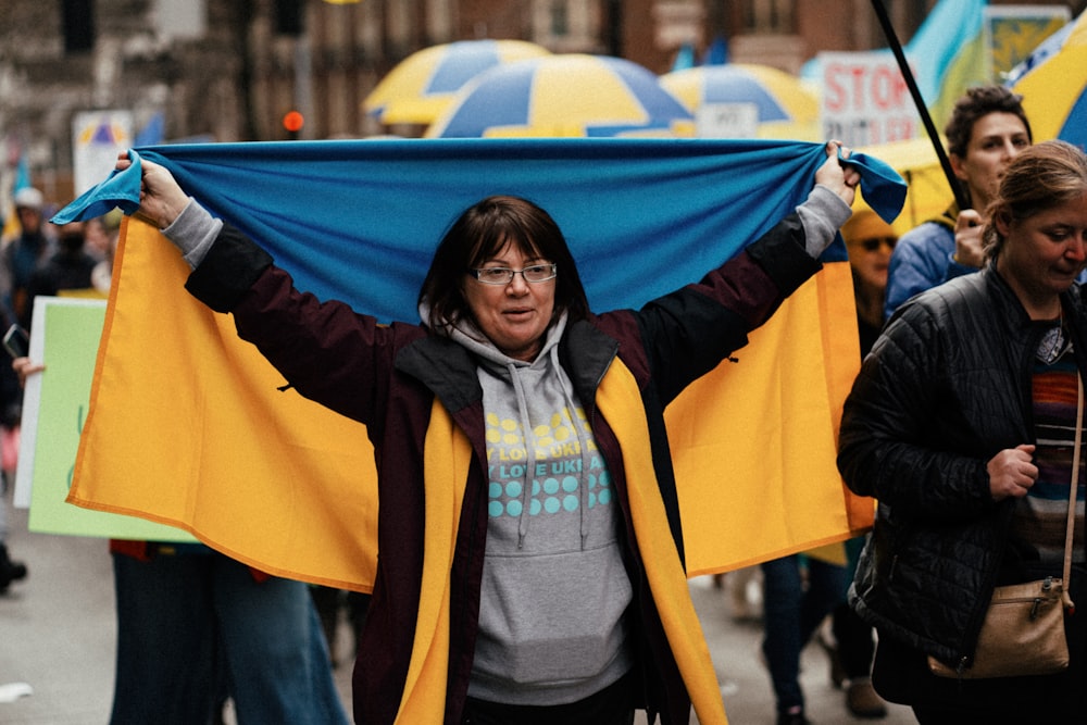 a woman holding a blue and yellow scarf over her head