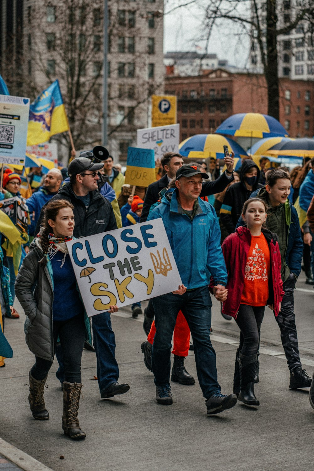 a group of people walking down a street holding signs