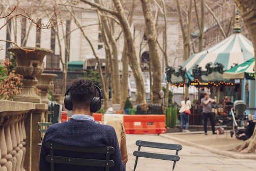 A serene outdoor scene with a person sitting on a bench, headphones on, listening to a podcast in the early morning light.