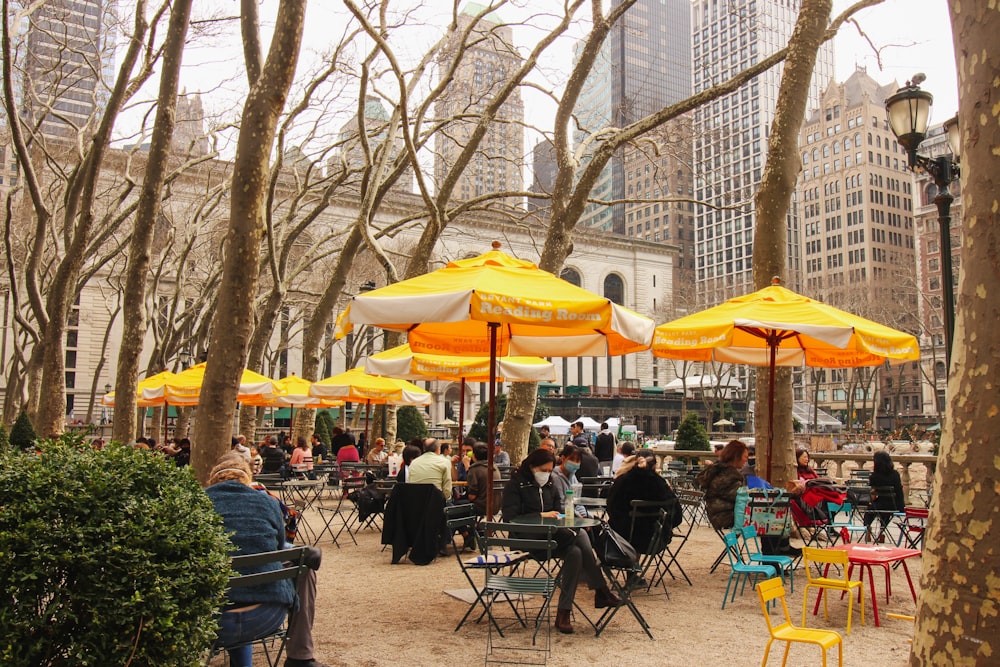 a group of people sitting at tables under yellow umbrellas