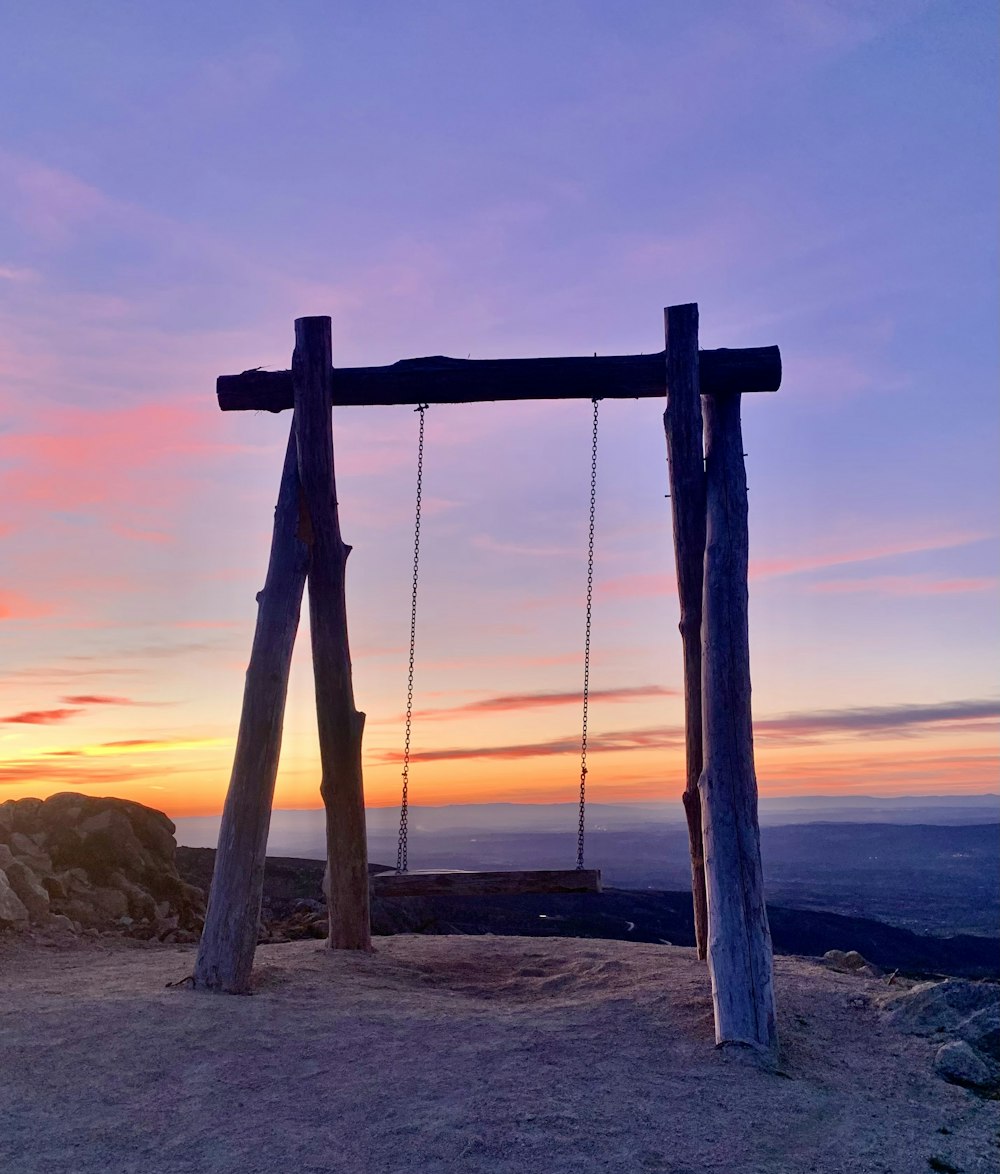 a wooden swing sitting on top of a hill